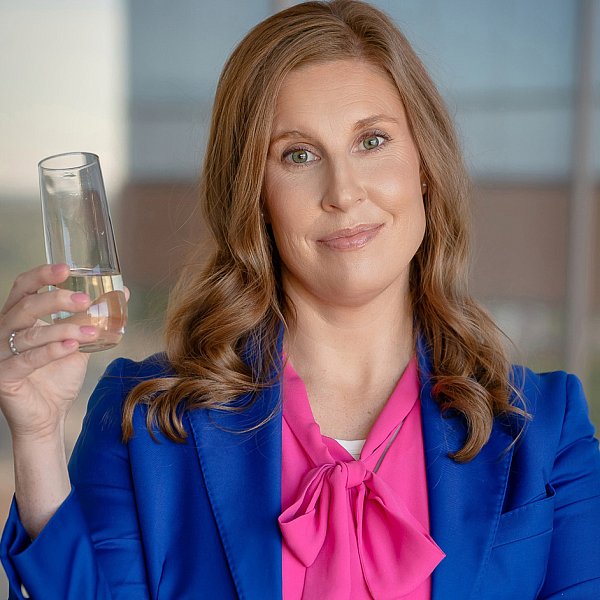 photo of an St. Louis executive coat in a blue coat with a pink blouse holding champaign