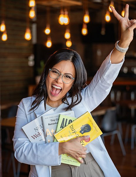Photo of a happy st. Louis marketing business owner woman wearing glasses and holding books. 
