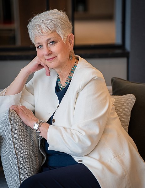 Portrait of a 65-year-old professional St. Louis woman coach with white hair in a white suit coat. 