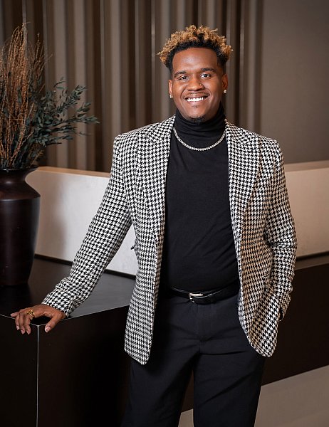 Portrait of a Black professional man in a black-and-white suit coat. 