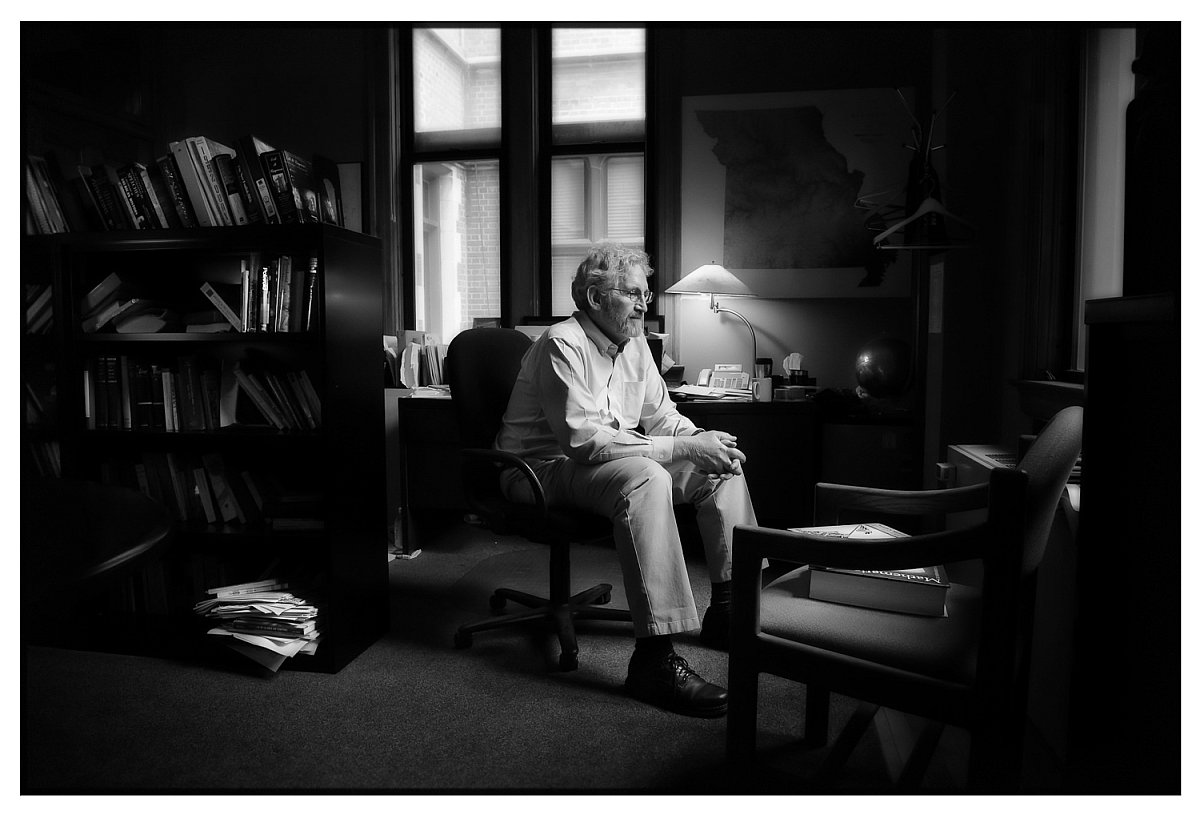 Dean of the University of Missouri–St. Louis Honors College, sitting in his office, photo in black and white. 