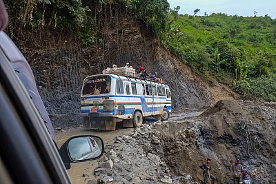 Photograph of a bus traveling through Myanmar on treacherous roads after a landslide. 