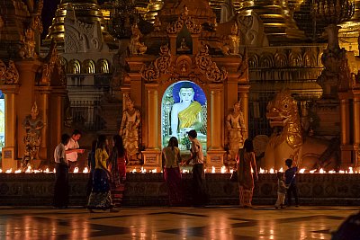 Color photograph at night.  Color photograph of devotees offering candles to Buddha in the evening at Shwedagon Temple in Yangon, Myanmar. 